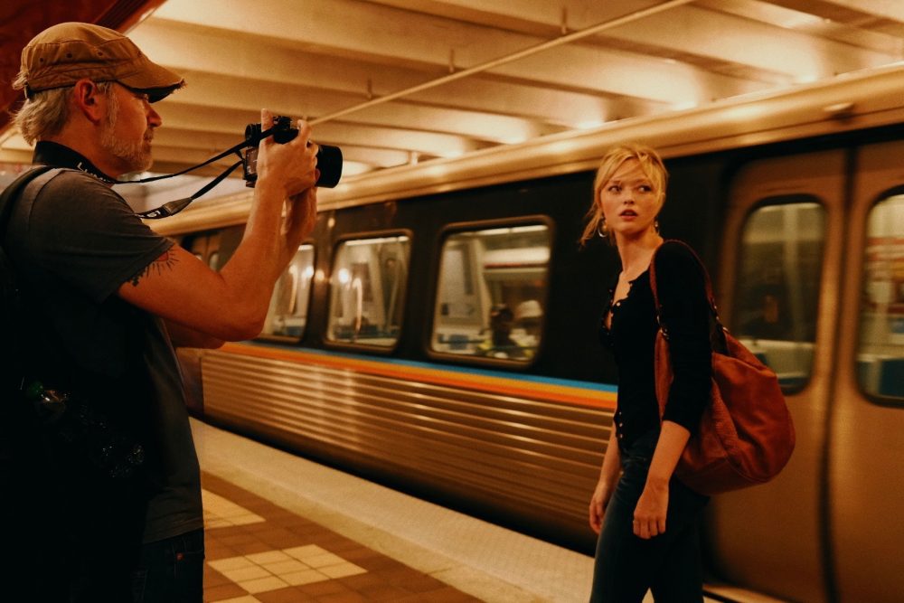 Young woman is photographed on a platform in front of a passing train